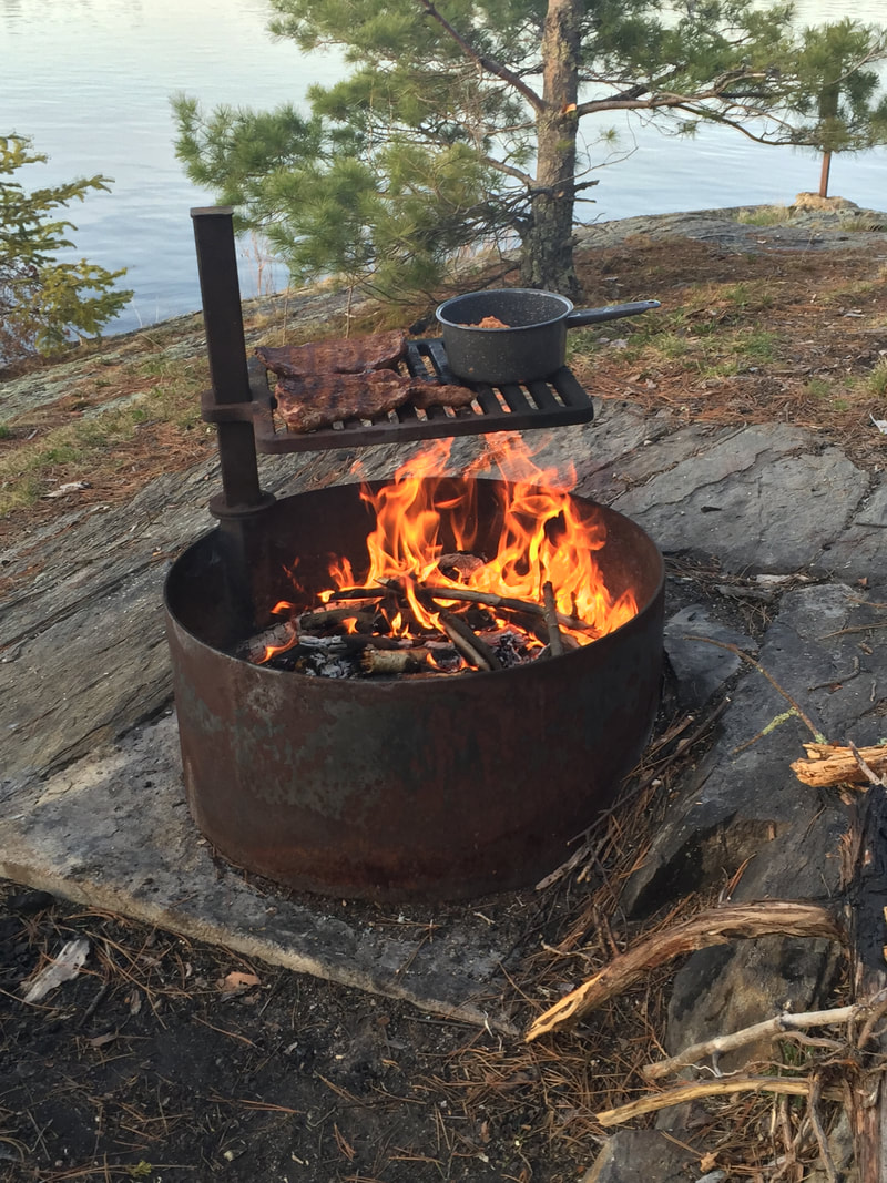 dinner-is-cooking-over-an-open-fire-in-vnp_orig a pot that is sitting on the side of a river